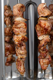 Cooking pork meat in an electric kebab maker on vertical skewers