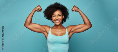 Tableau sur toile attractive young african american woman flexing her biceps on teal background