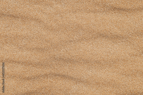 Fototapeta Naklejka Na Ścianę i Meble -  Close-up  background brown sand wave with rippled dunes. Top view. Space for text. Sand summer texture.