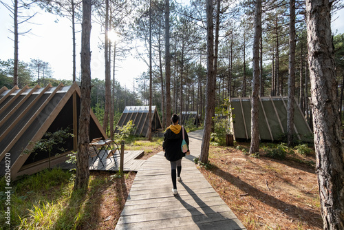 A woman walking in the forest. Wooden triangular houses in the forest. Athlete woman walks in the forest.
