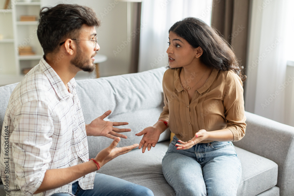 Angry indian couple having quarrel experiencing crisis in relationship, sitting on sofa and having conflict at home. Marital problems, divorce concept Angry indian couple having quarrel experiencing crisis in relationship, sitting on sofa and having conflict at home. Marital problems, divorce concept
