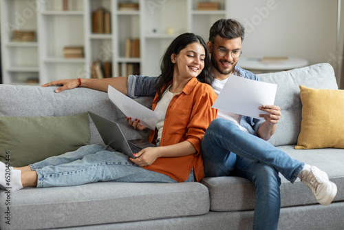 Billede på lærred Happy indian couple checking documents, spouses reading insurance agreement or p