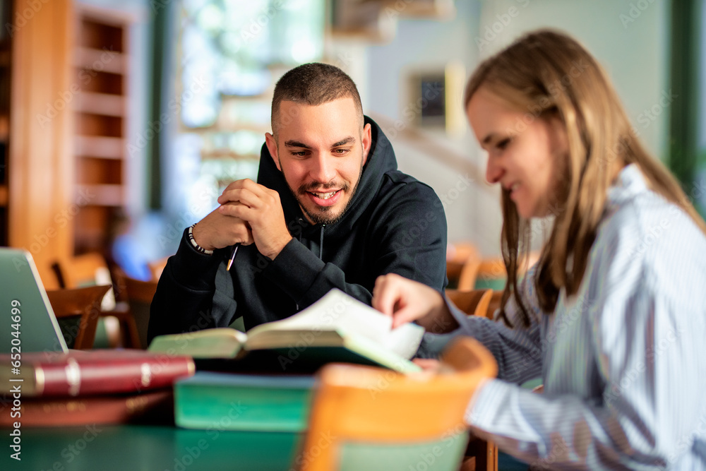 Young man supporting visaully impaired woman to study in library Young man supporting visaully impaired woman to study in library