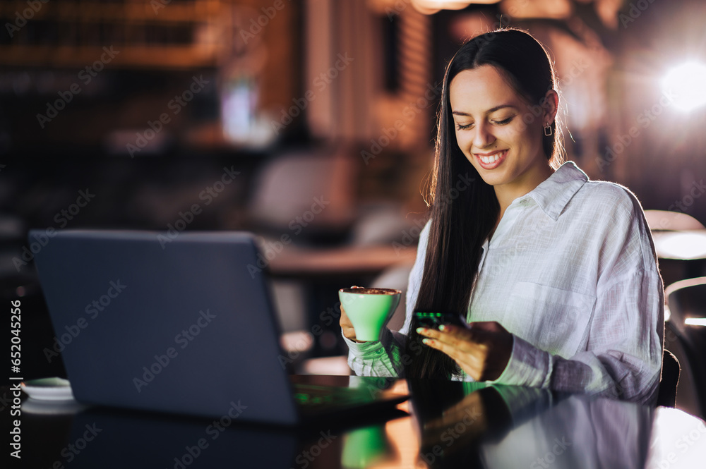 Portrait of a happy casual executive sitting in a coffee shop and typing on the phone while smiling at it and drinking coffee. Portrait of a happy casual executive sitting in a coffee shop and typing on the phone while smiling at it and drinking coffee.