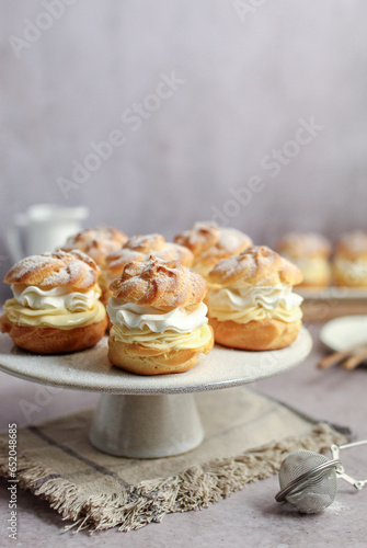 Cream puffs filled with vanilla cream and whipped cream on a white plate.