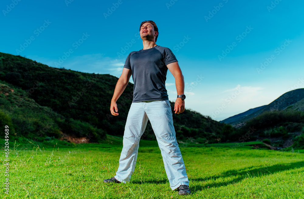 Obraz premium Handsome young man standing and breathing in mountain valley at twilight