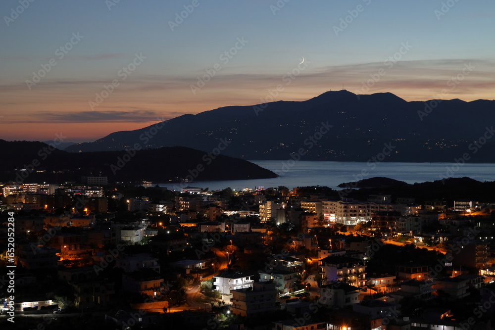 Night view of the city Ksamil in Albania on the background of Corfu island and moon. Amazing Albanian Riviera