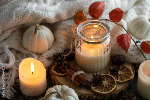 Autumn home composition with aromatic candle, dry citrus, cinnamon, anise. Aromatherapy on a grey fall morning, atmosphere of cosiness and relax. Wooden background close up