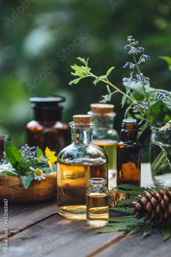 Natural organic essential oil in small glass bottles on wooden background. Homemade production for spa, sauna, bath. Relaxation, alternative medicine, remedy, naturopathy, pure ingredients