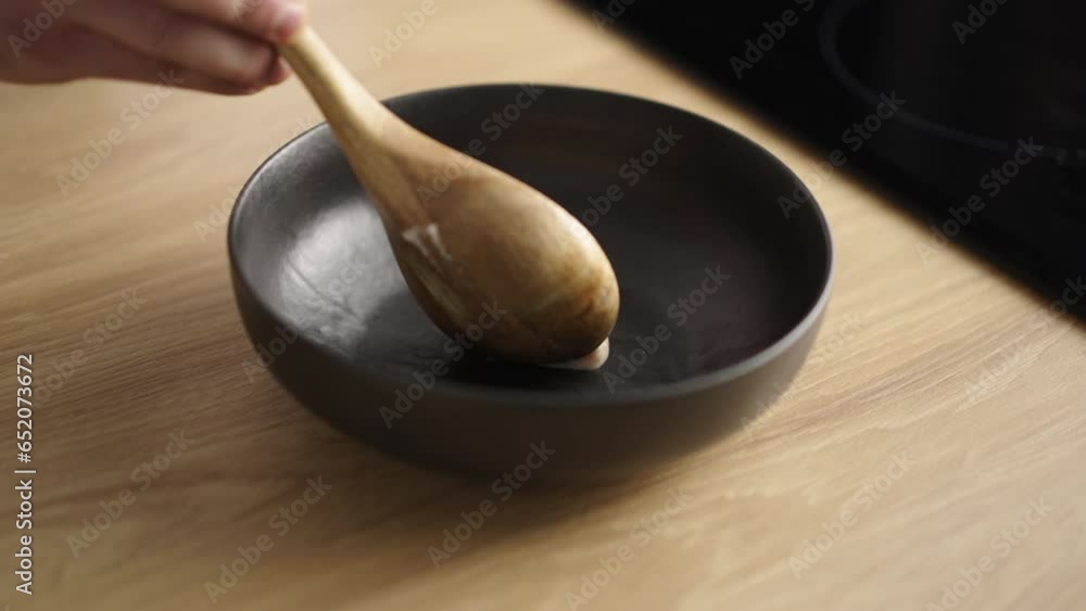 Close-up shot of a cook putting fresh dough on wooden table with a spoon in slow-motion Close-up shot of a cook putting fresh dough on wooden table with a spoon in slow-motion