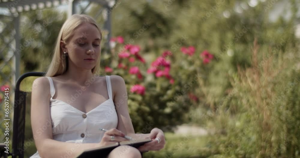 Young blonde female artist discussing work with crop model in garden Young blonde female artist discussing work with crop model in garden