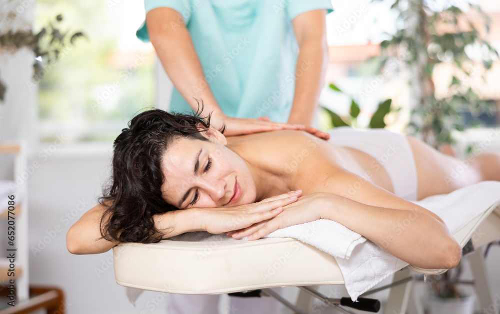 Obraz premium Portrait of happy woman enjoying relaxing massage by professional masseur
