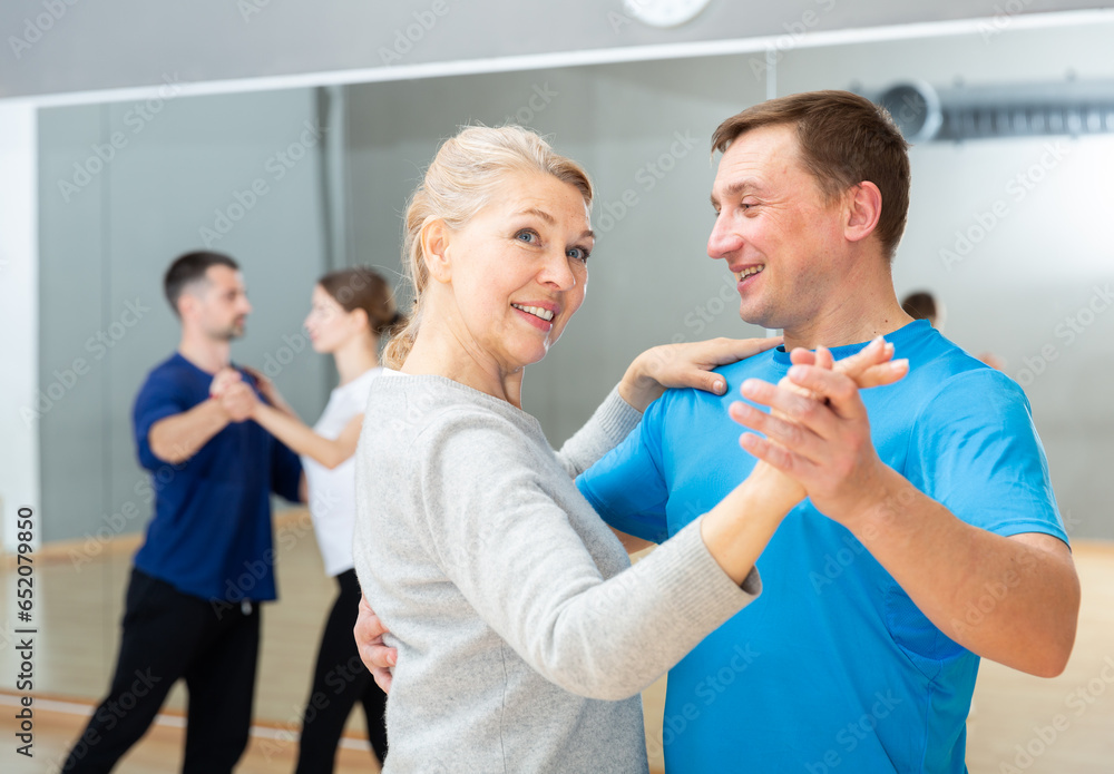 Obraz premium Mature dancing couple enjoying social dance during group class in modern studio