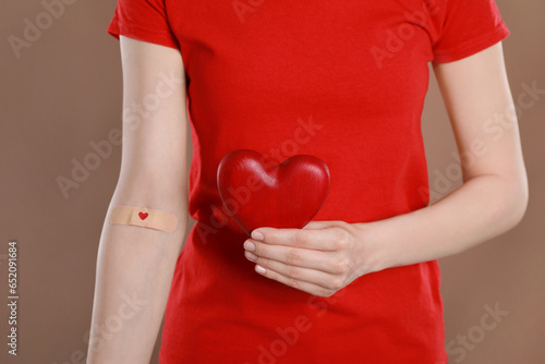 Wallpaper Mural Blood donation concept. Woman with adhesive plaster on arm holding red heart against brown background, closeup Torontodigital.ca