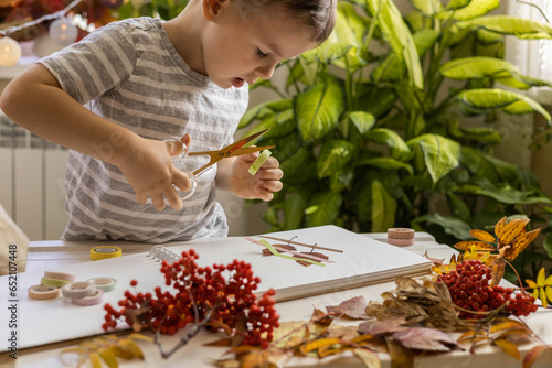 A child makes a herbarium from autumn colorful leaves. Happy autumn time.