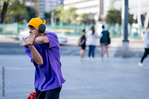 Dancing latino young man with headphones listening to music performing various freestyle dance outdoors having fun. hiphop dancing, street dancing