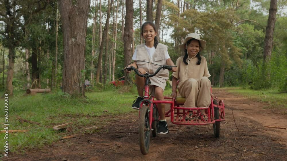 Young girl and her sister riding the tricycle with cargo bike together Young girl and her sister riding the tricycle with cargo bike together