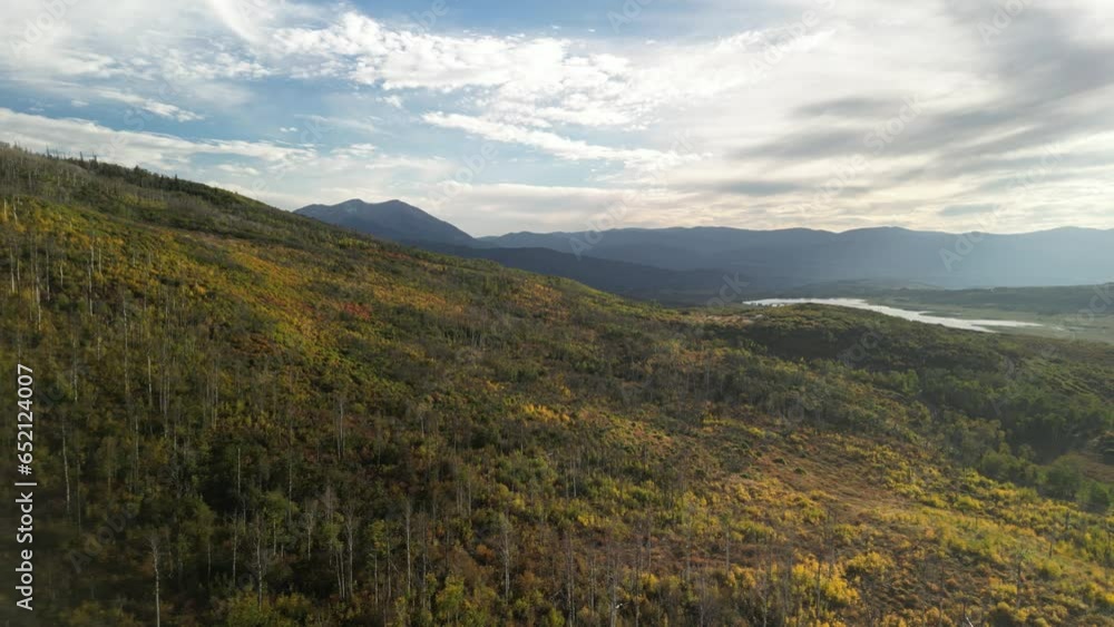 Aerial of fall colors of aspen trees on rolling mountains near Aspen Colorado in autumn at sunset with lake view Aerial of fall colors of aspen trees on rolling mountains near Aspen Colorado in autumn at sunset with lake view