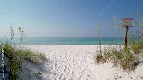 AWalk to though sand dunes with sea oats on white sand beach of Pensacola Florida on the Clear waters of the Gulf of Mexico on a bright sunny summer day photo