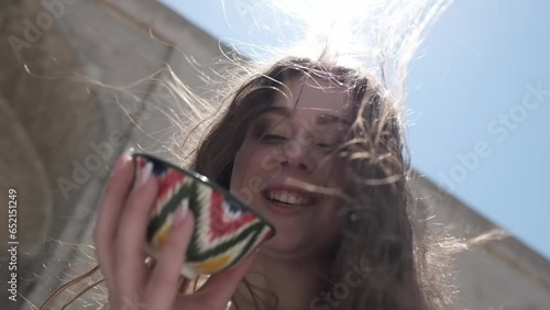 A young woman with long hair holding a painted ceramic tea cup with an Uzbek ornament in her hands photo