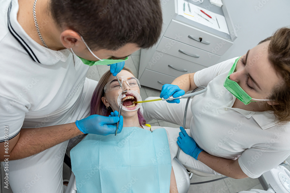 patient is lying in dentistry where she is being treated by male somatologist female assistant patient is lying in dentistry where she is being treated by male somatologist female assistant