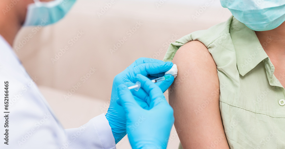 Fototapeta premium Vaccination, Doctor man injection coronavirus vaccine to young woman her shoulder, female patient in medical face mask, Covid-19 pandemic outbreak Medicine And Health Care Concept