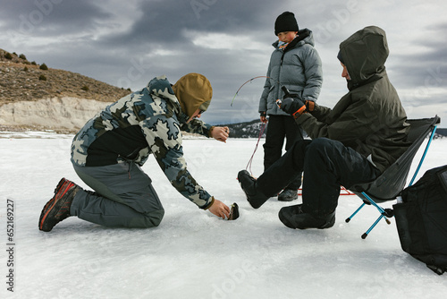 Quadro su tela Family pulls out a fish in ice hole on frozen lake in winter adventure