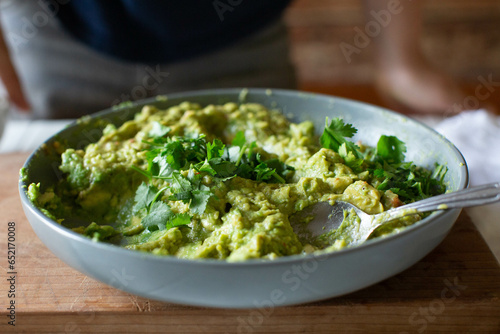 Freshly made guacamole in gray bowl with chopped cilantro