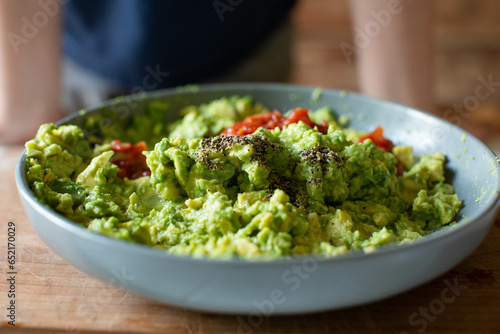 Freshly made guacamole with tomatoes and pepper  in gray bowl with