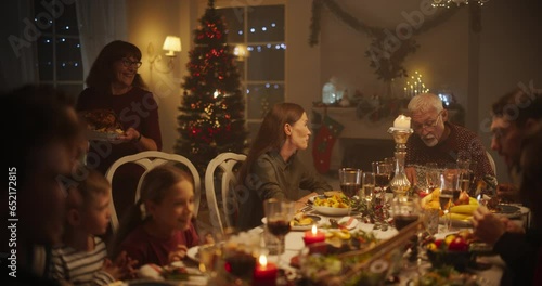 Families with Kids and Friends Gather for a Joyful Christmas Dinner with Beautifully Roasted Turkey. Home Is Filled with Festive Winter Atmosphere, Grandmother Bringing the Main Course to the Table photo