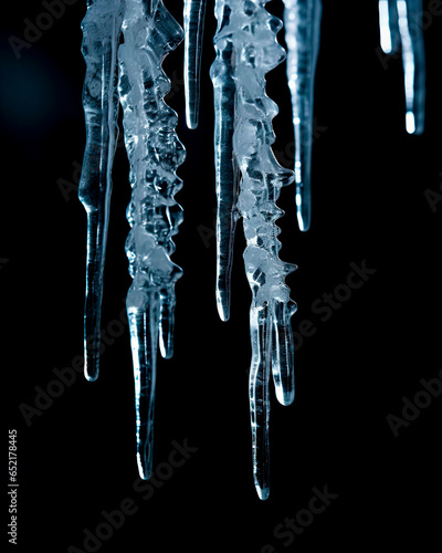 Frozen Icicles hanging. Isolated on a black background with shallow field of view. Concept of winter, cold and freezing. Close up. 