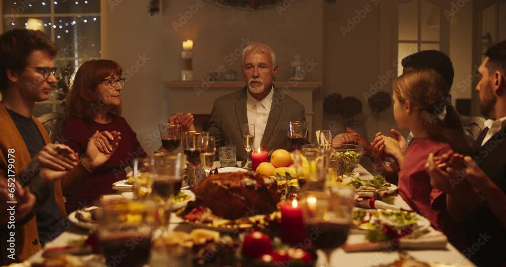 Portrait of a Senior Man Sitting at the Head of the Festive Table with Family and Children, Praying Before Eating a Turkey Dinner. Religious Male Blessing Christmas Food, Thanking God and Jesus Christ Portrait of a Senior Man Sitting at the Head of the Festive Table with Family and Children, Praying Before Eating a Turkey Dinner. Religious Male Blessing Christmas Food, Thanking God and Jesus Christ