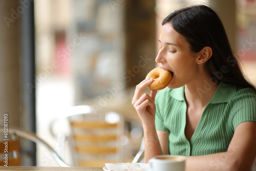 Woman in a restaurant eating doughnut for breakfast