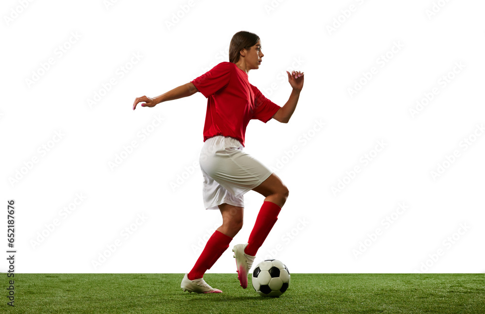 Motivated young sportsman, girl, football player in motion, dribbling ball isolated over white background. Success