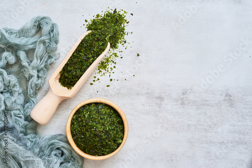 top view flat lay green nori seaweed kelp alga powder flake with wood bowl scoop food table white background. nori seaweed kelp alga powder flake food background. nori seaweed kelp alga powder flake