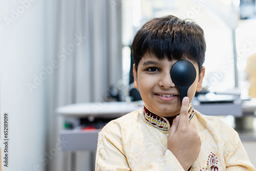 Indian boy examining eyesight checkup vision farsightedness examines ophthalmological hospital. doctor using occluder for eye test ophthalmological for indian boy.