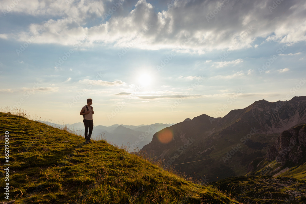 Germany, Bavaria, Oberstdorf, man on a hike in the mountains looking at view at sunset Germany, Bavaria, Oberstdorf, man on a hike in the mountains looking at view at sunset