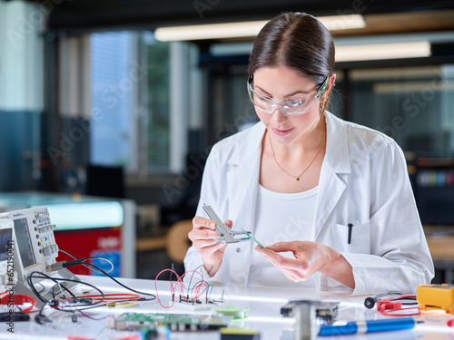 Trainee measuring circuit board with caliper in laboratory photo