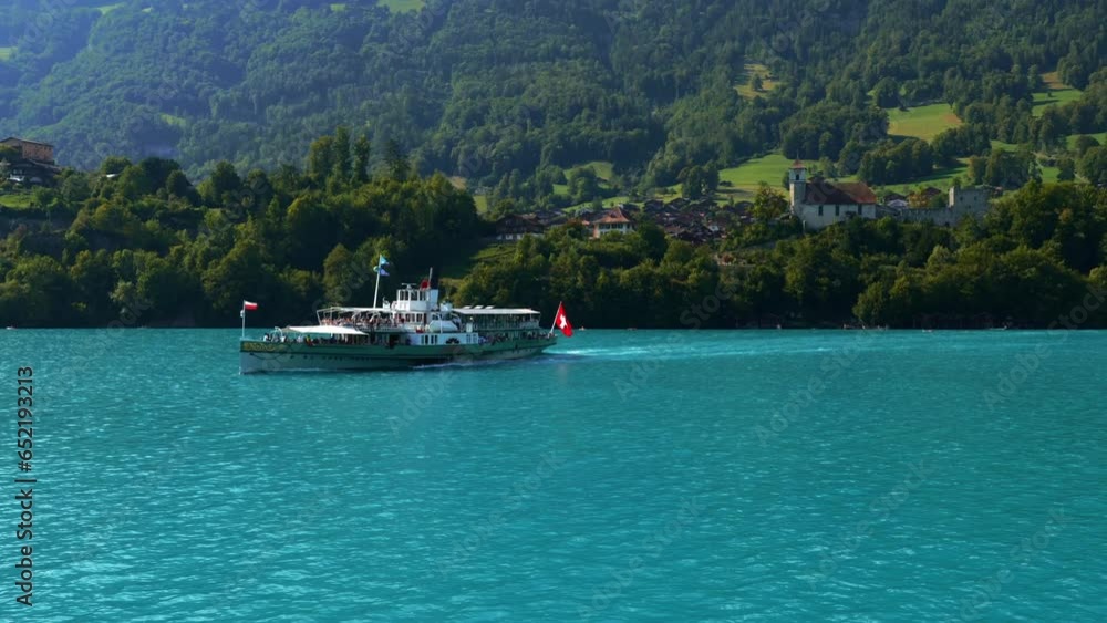 Passenger Ship with Swiss Flag and Mountain on Lake Brienz and Ringgenberg Church and Castle in a Sunny Summer Day in Bernese Oberland, Bern Canton, Switzerland, Europe Passenger Ship with Swiss Flag and Mountain on Lake Brienz and Ringgenberg Church and Castle in a Sunny Summer Day in Bernese Oberland, Bern Canton, Switzerland, Europe