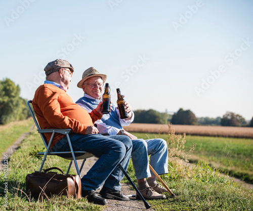 Two old friends sitting in the fields, drinking beer, talking about old times photo