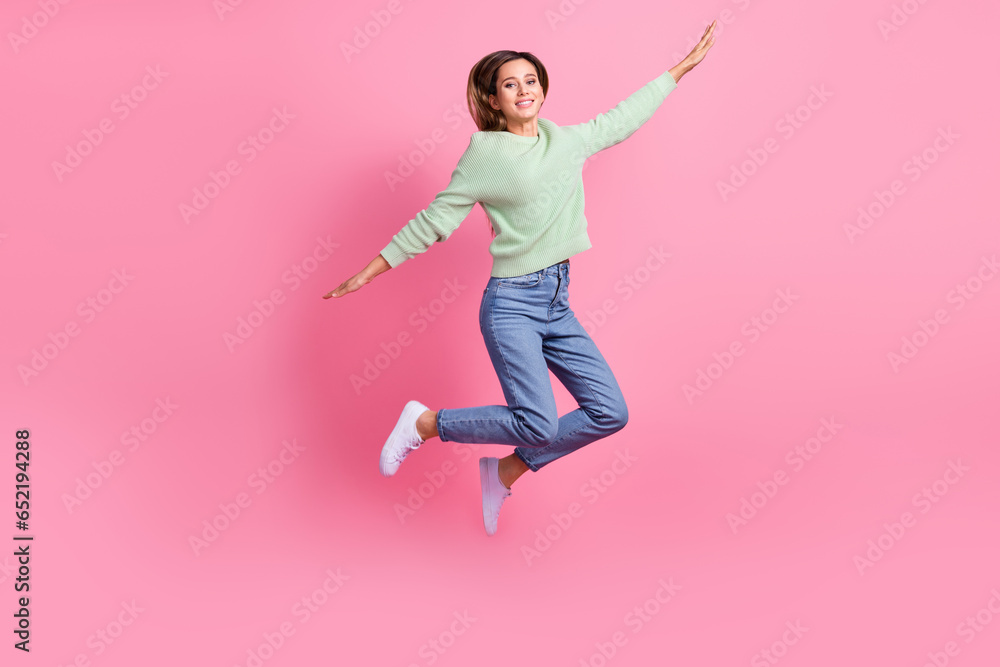 Full body size photo of jumper careless woman brown hair flying hands wings free atmosphere shopper isolated on pink color background