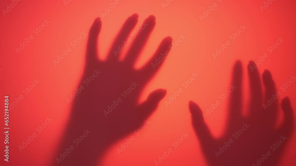 Video of hands of adult lady slowly appear, gently touching red wall illuminated by contour light with palms and fingers, attempting to grab. Woman creating scary atmosphere of Halloween holiday. Video of hands of adult lady slowly appear, gently touching red wall illuminated by contour light with palms and fingers, attempting to grab. Woman creating scary atmosphere of Halloween holiday.