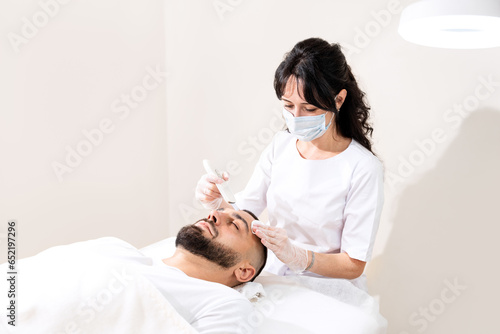Ultrasound facial cleansing for young handsome man in professional beauty clinic.