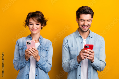 Photo of cute sweet couple best friends wear stylish denim clothes use iphone read instagram facebook isolated on yellow color background