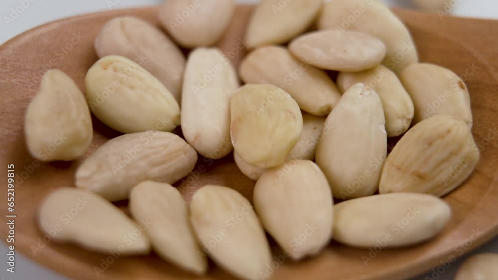 Peeled raw almond nuts falling in slow motion on a wooden spoon close up. Healthy wholesome dietary ingredient Peeled raw almond nuts falling in slow motion on a wooden spoon close up. Healthy wholesome dietary ingredient
