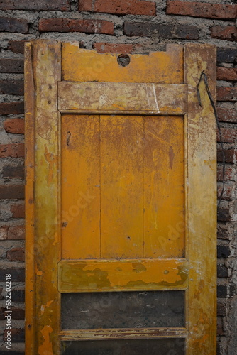 the texture of an old, fragile door with a red brick background