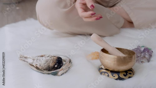 Woman's feet approaching and sitting Gyan mudra pose to meditate burning white sage and quartz crystals and a Tibetan bowl on the floor of her home in the ceremonial padmasana and holistic ritual pose photo