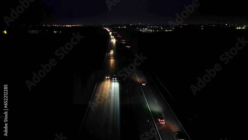 Aerial view of cars driving on a dual carriageway on dark, lights falling on the road, night car traffic.