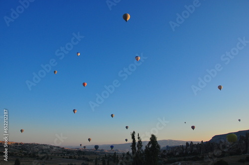 Multiple hot air balloons at sunrise with blue sky