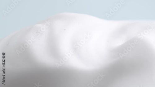 Hair foam mousse on light blue background, macro. Beauty background. Close up of white cloud of hair mousse or shaving foam.
